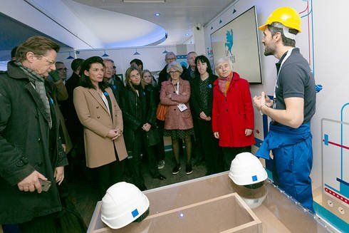 Christelle Morançais, présidente de Région avec groupe de personnes autour d'un homme en habit de chantier qui parle, dans une salle